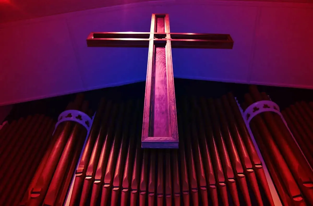 The illuminated cross and organ pipes inside New Brighton Methodist Church